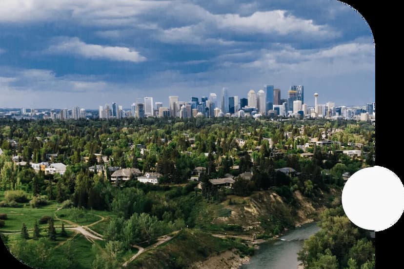 Treed-residential-neighbourhoods-in-Calgary-Alberta-with-the-skyscrapers-of-downtown-in-the-distance-on-a-cloudy-day